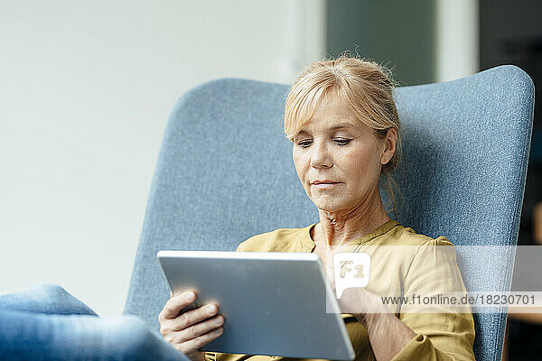 Mature businesswoman using tablet PC on armchair