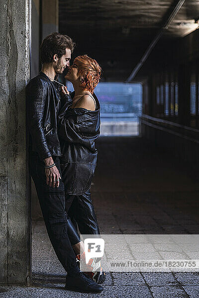 Romantic boyfriend with girlfriend leaning on wall at underpass