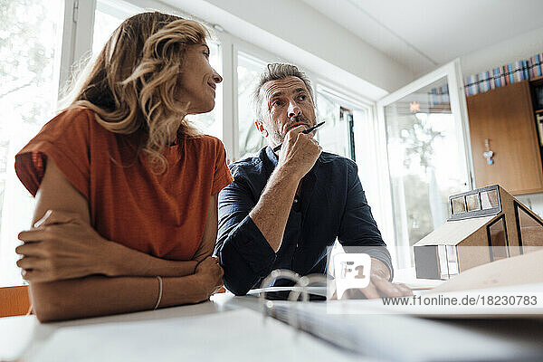 Mature man and woman discussing over real estate contract at table