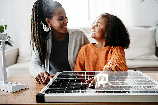 Happy mother and daughter with solar panel at home