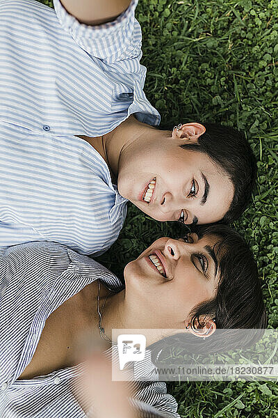 Smiling lesbian couple looking at each other lying on grass