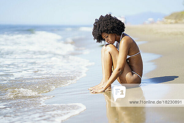 Ernsthafte Frau sitzt an einem sonnigen Tag am Strand
