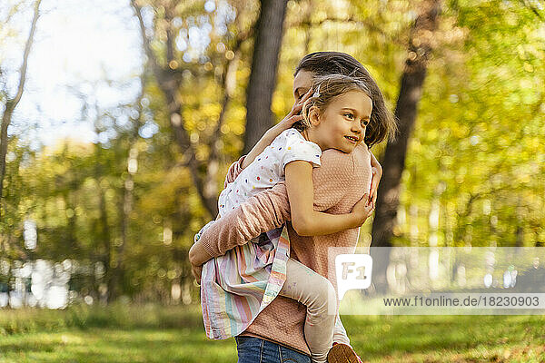 Mother carrying daughter in park