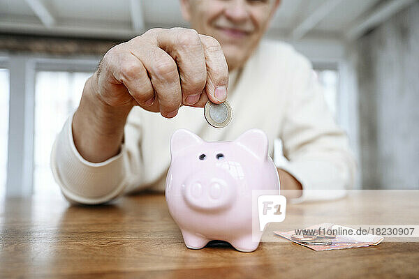 Man putting coin into piggy bank at home