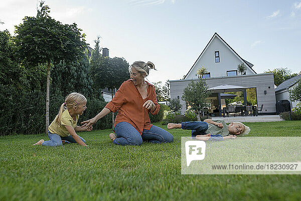 Fröhliche Mutter mit Kindern  die im Garten spielen