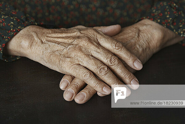 Senior woman with wrinkled hands on table