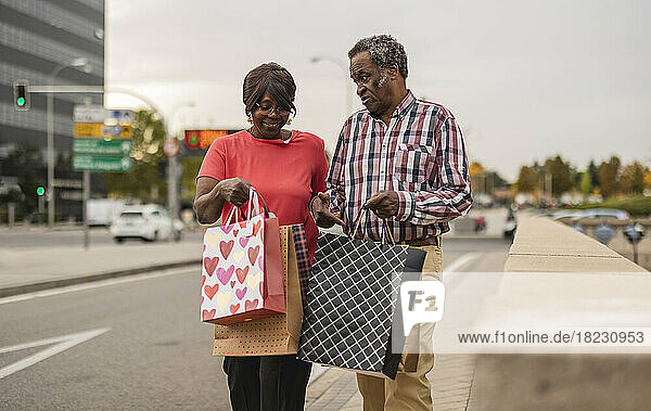 Älteres Paar redet miteinander und hält Einkaufstüten in der Hand