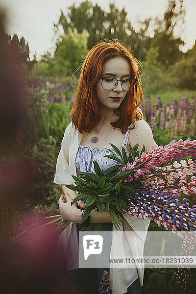 Redhead teenage girl standing with lupin flowers