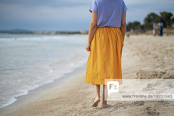 Frau geht am Strand auf Sand