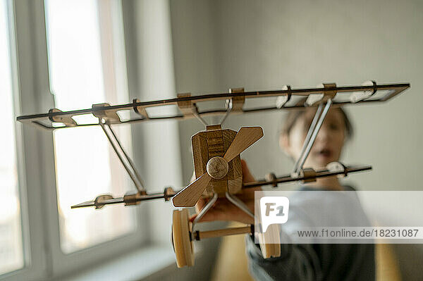 Boy playing with wooden toy airplane