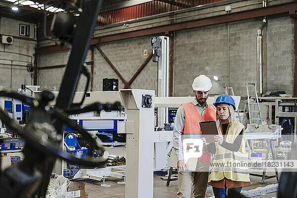 Engineer with colleague using tablet computer at industry