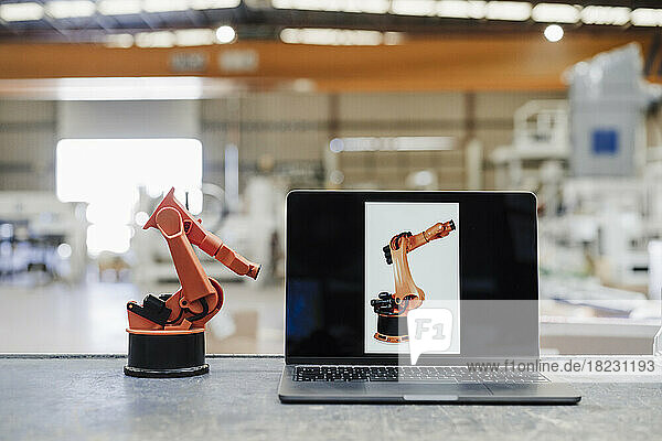 Laptop and robotic arm on desk at industry