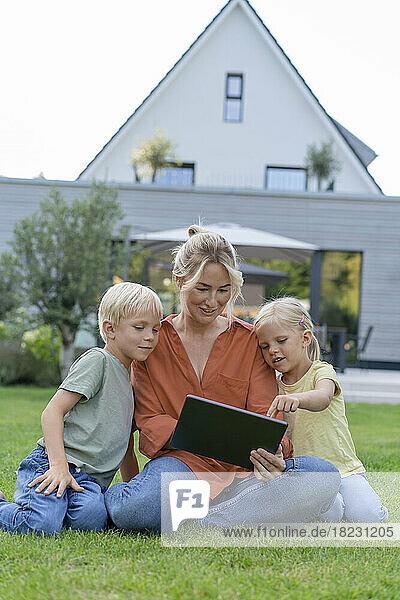 Happy mother sharing tablet PC with children in garden