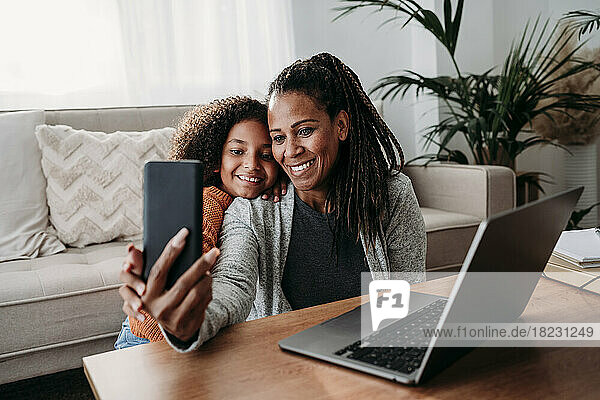 Glückliche Mutter und Tochter unterhalten sich zu Hause per Videoanruf über das Smartphone