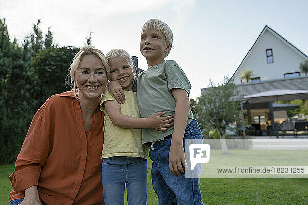 Smiling mother with son and daughter in garden