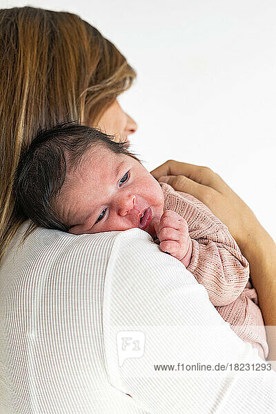 Newborn daughter resting on mother's shoulder
