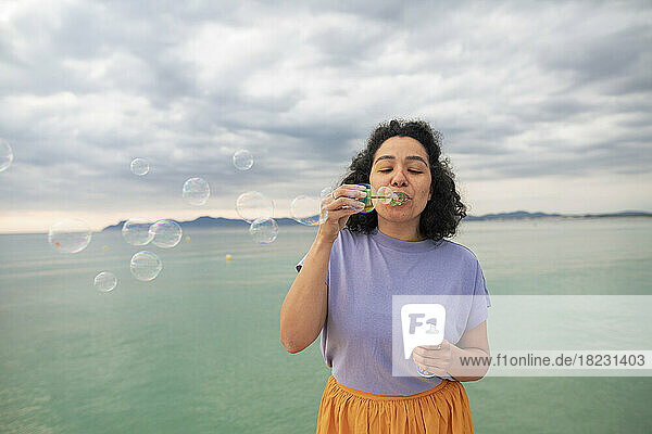 Woman blowing bubbles in front of sea