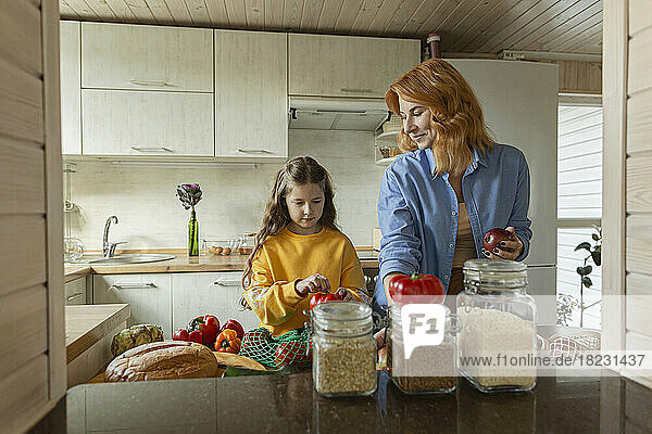 Mutter und Tochter packen frische Lebensmittel in der Küche aus