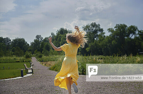 Fröhliche Frau tanzt und hat Spaß im Park an einem sonnigen Tag