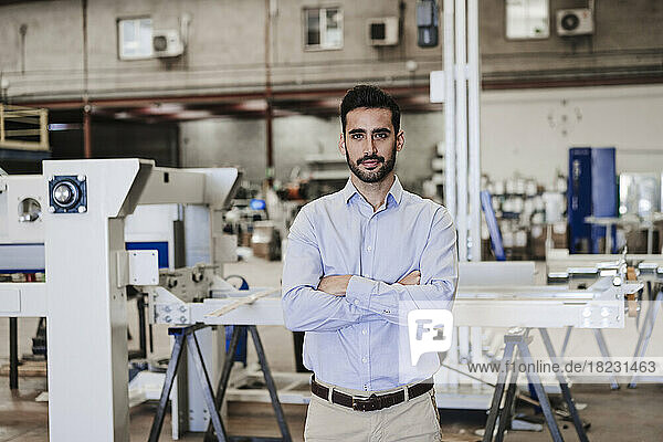 Confident engineer with arms crossed standing in industry