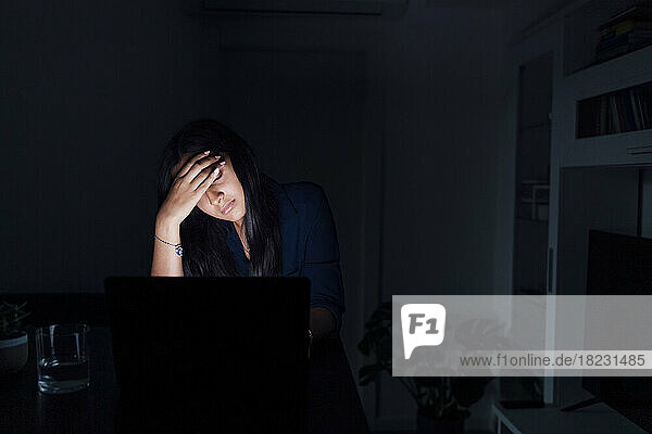 Tired young woman with laptop at home