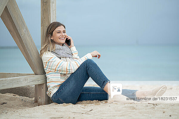 Smiling beautiful young woman talking on smart phone at beach