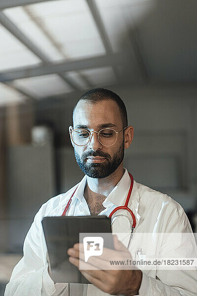 Doctor using tablet PC in hospital seen through glass