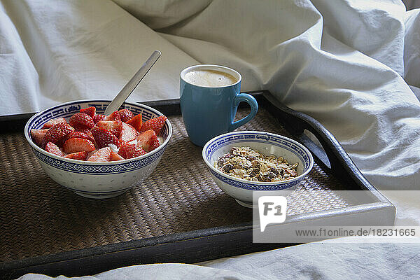 Tablett mit einer Tasse Kaffee  Müsli und Joghurt mit Erdbeeren