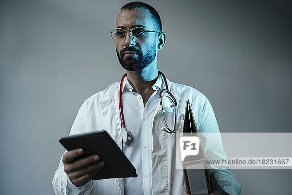 Doctor holding tablet PC in front of wall