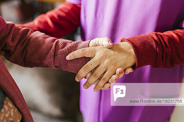 Young caregiver holding hand of senior woman at home
