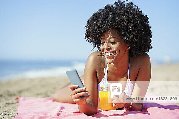 Happy woman using smart phone at beach on sunny day