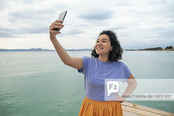Smiling woman taking selfie in front of sea