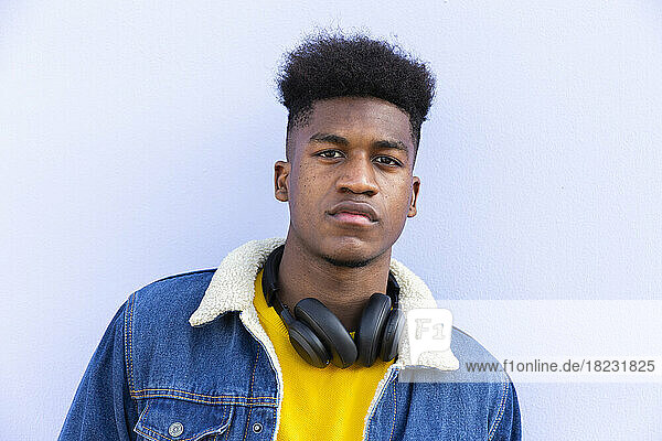 Young man with wireless headphones in front of white wall
