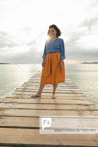 Lächelnde Frau steht auf einem Steg inmitten des Meeres