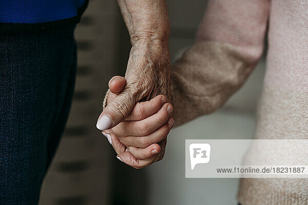 Grandmother holding granddaughter's hand at home