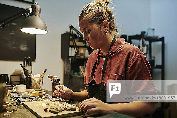 Jeweller working at workbench in workshop