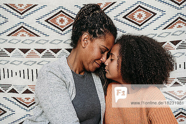 Woman embracing daughter in front of patterned backdrop