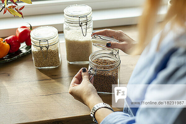 Women opening jar with seeds in kitchen