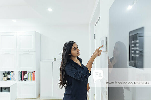 Frau benutzt Smart-Home-Gerät an der Wand