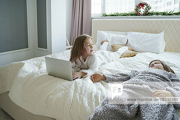 Girl lying on bed with brother at home