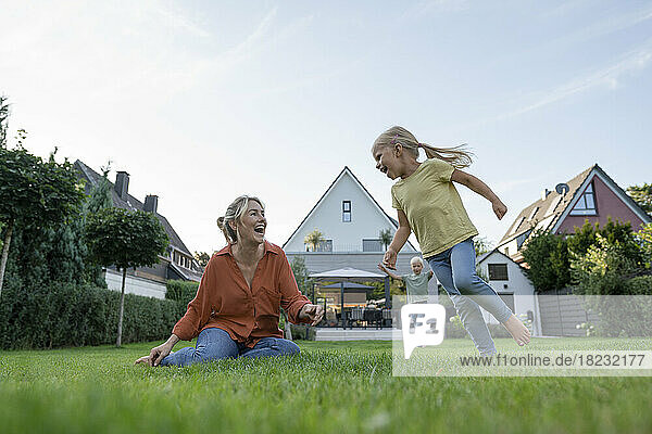 Happy woman with daughter and son enjoying in back yard