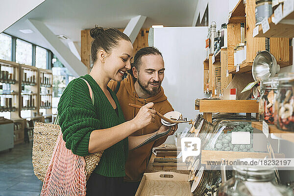 Woman with spoon by man in zero waste store