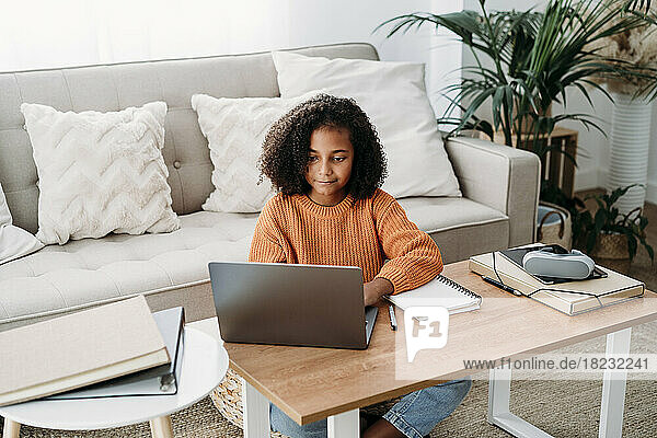 Mädchen benutzt Laptop und lernt zu Hause im Wohnzimmer