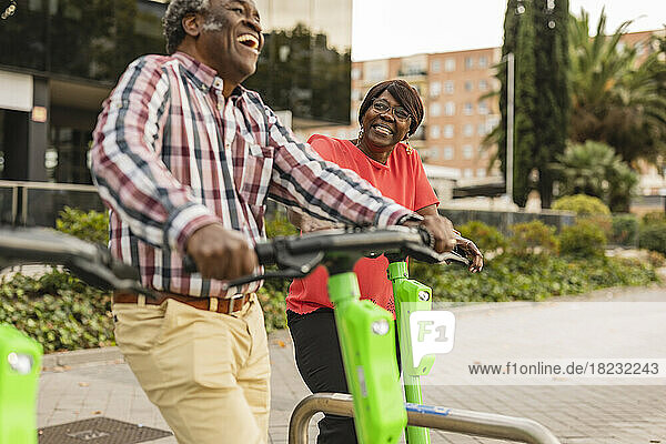 Happy senior couple spending leisure time with push scooters