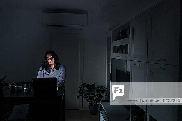 Sad young woman using laptop in living room at home