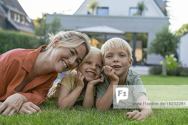 Happy mother with children leaning on elbows in garden