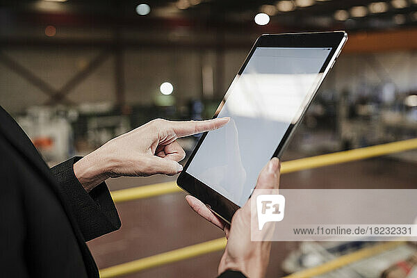 Hand of businesswoman using tablet PC at factory