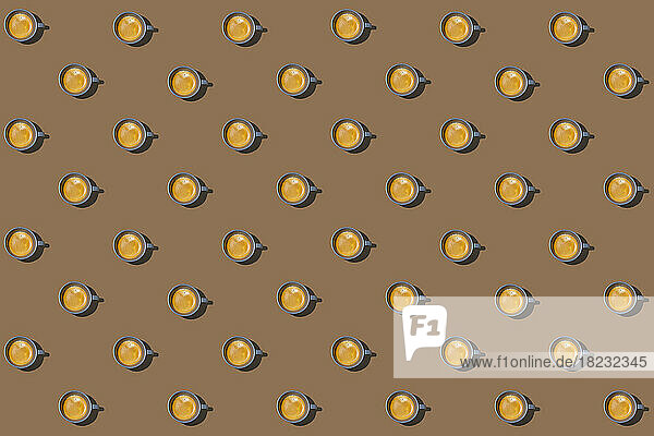 Pattern of cups of coffee standing in rows against brown background