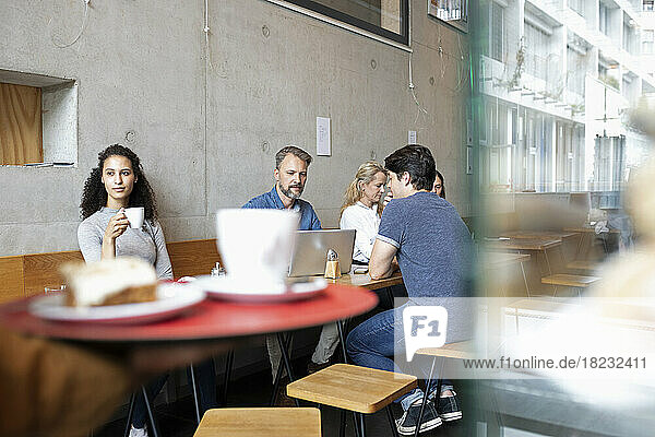 Men and women sitting and having coffee in cafe