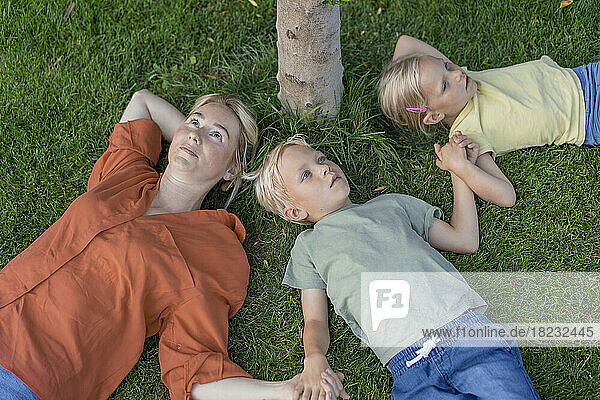 Woman with children lying down on grass in back yard